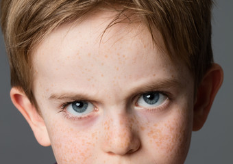 displeased young boy with big blue eyes for childhood attitude