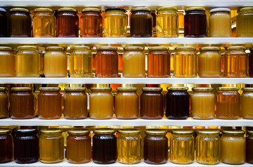 Jars of different honey varieties stocked on a shelf - Powered by Adobe