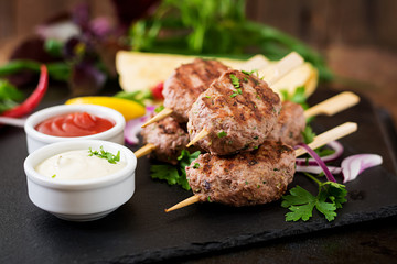 Appetizing kofta kebab (meatballs) with sauce and tortillas tacos on black background