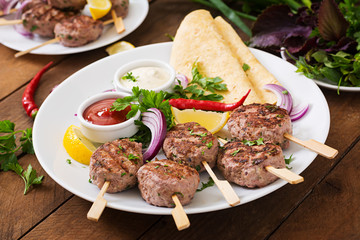 Appetizing kofta kebab (meatballs) with sauce and tortillas tacos on a white plate