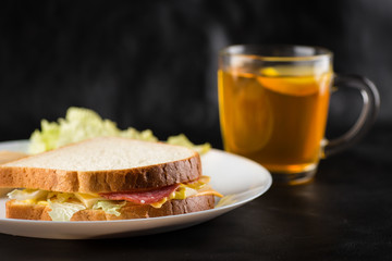 Sandwich, cheese sandwich with greens and sausage with tea in the background 