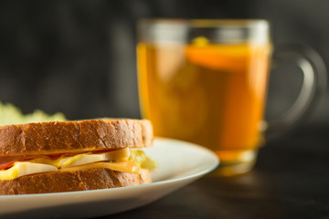 Sandwich, cheese sandwich with greens and sausage with tea in the background 