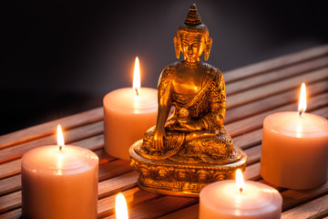 Bronze Buddha with warm lighted candles over wooden background - 121969876
