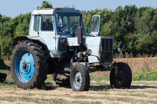 Old tractor in summer on field.