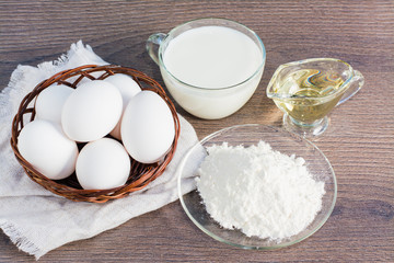 Пшеничная мука, куриные яйца, молоко, подсолнечное масло на деревянном столе