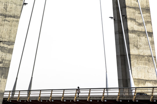 Mujer cruzando el gran puente de la ciudad por la mañana para acudir a trabajar.