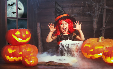 Halloween. child girl witch preparing  potion in cauldron with p
