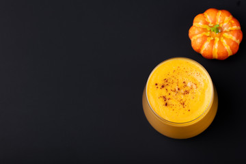 Pumpkin smoothie with pumpkin pie spices on a black slate stone background Top view. Copy space.