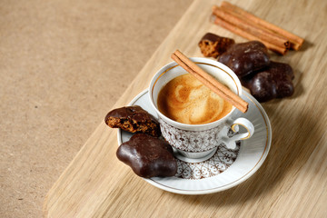cup of hot coffee, cinnamon sticks, cookies and chocolate on wooden table