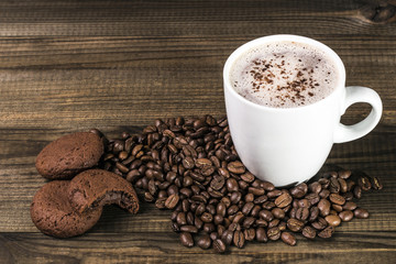 cup of coffee with coffee beans and cookies on wooden table. Image with copy space