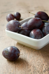 quetches et bol blanc sur table en vieux bois 