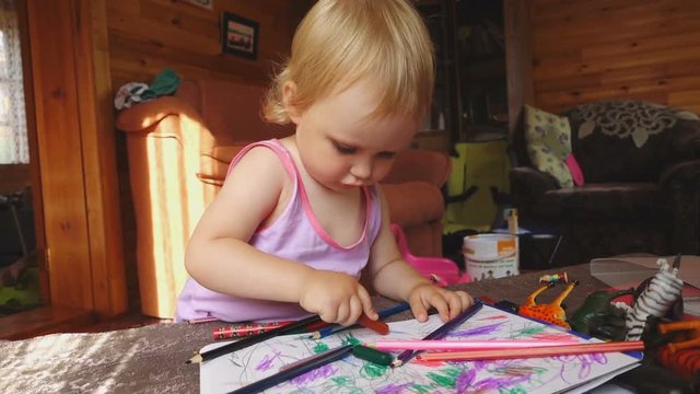 Sweet little girl draws with colored pencils