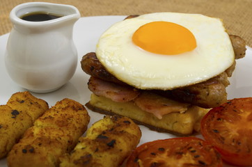 Waffle Stack Breakfast
Breakfast of waffles, bacon, egg, sausage in a stack with tomato, hash browns and a jug of maple syrup