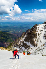 Group of climbers rises thru snow towards the summit. View from above. Weather is good. Mountaineering in High Tatras, Slovakia