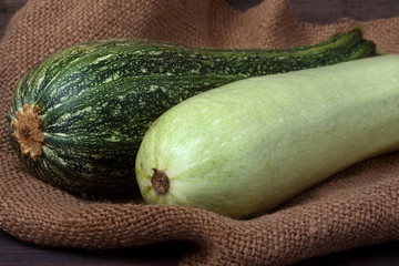 green zucchini and courgette on sackcloth  wooden background