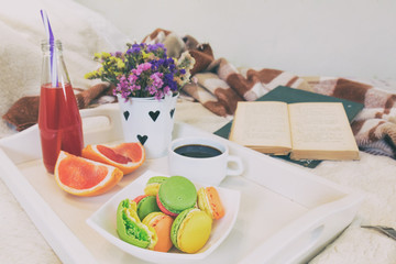 Breakfast in bed with hot coffee and macaroons. Healthy breakfast kept on bed with books and...