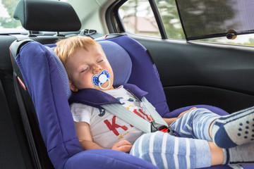 Little boy is sleeping in the car safety seat