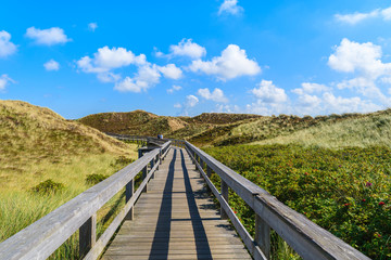 Fototapeta na wymiar Wooden walkway to beach among sand dunes on Sylt island, Germany