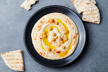 Hummus, chickpea dip, with spices and pita, flat bread in a black plate. Top view