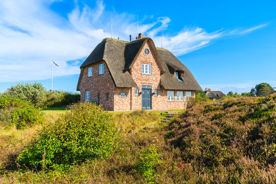 Traditional red brick house with thatched roof on meadow near Wenningsted village on Sylt island, Germany