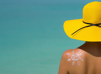Woman with sun-shaped sun cream on beach