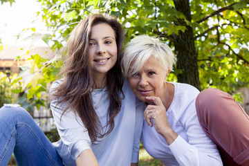 pretty mom and daughter consult the laptop under a tree in autum