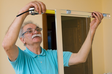 senior man installing and measuring a shower box, do-it-yourself concept