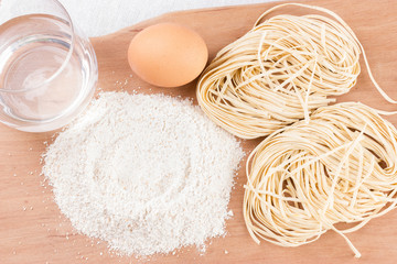 Ingredients for pasta and homemade pasta on wooden background