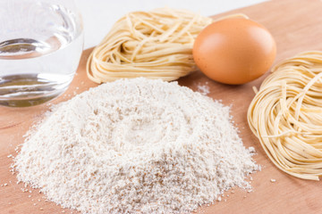 Ingredients for pasta and homemade pasta on wooden background