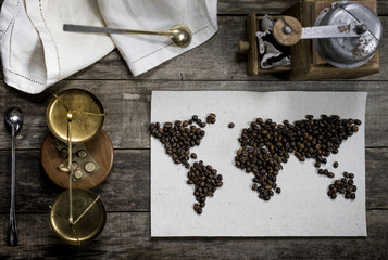 map of the world, lined with coffee beans on old paper. Eurasia, America, Australia, Africa. vintage. Black coffee, ground coffee, scales, old hand grinder on old wooden table . top view. flat lay