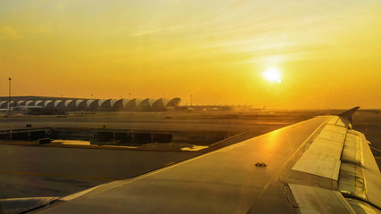 Fototapeta na wymiar Wing of an airplane flying with sunrise