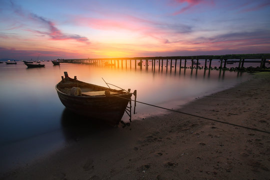 Small fishing boats moored beached on the beach during time the sunset and the beautiful natural of the colorful sky at Bang Phra beach , Chonburi province in Thailand