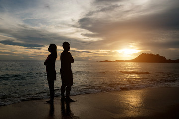 Couple silhouette breaking up a relation on the beach at sunset