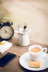 Coffee cup with sweets on the table with brown paper notes with a pen nearby.