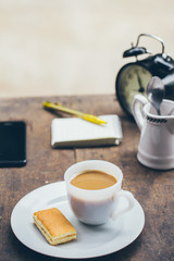 Coffee cup with sweets on the table with brown paper notes with a pen nearby.