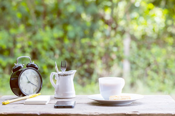 Coffee cup with sweets on the table with brown paper notes with a pen nearby. In the background is bokeh