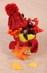 Autumn decoration with cup wrapped scarf and woolen cap on burlap