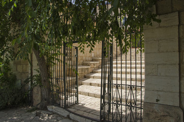 Wrought iron gate with sheltering tree and stone stairs in Yemin Moshe neighbourhood of Jerusalem