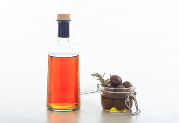 Bottle of vinegar and olives on white background