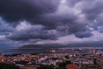 Sunset in the Port of Messina in Sicily Italy. Clouds and sunset light with night illumination.
