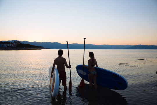 Silhouette of beautiful couple with sup surf and paddle at the ocean. Concept  lifestyle, sport, love