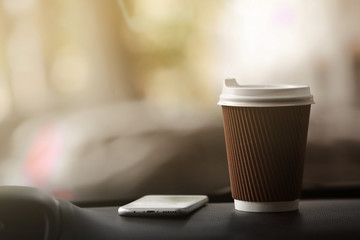 Cup of coffee and smartphone on car console
