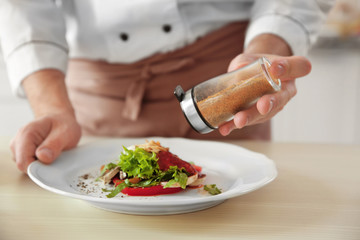 Chef cook adding pepper to dish, closeup