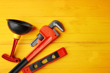 Plumber tools on yellow wooden background