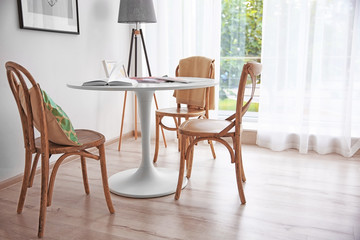 Modern white table and wooden chairs near window