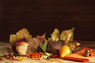 Autumn composition of leaves, berries and vegetables on wooden table. Thanksgiving day concept