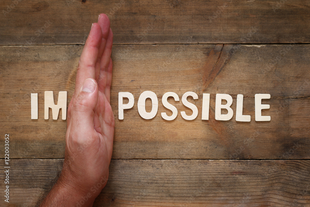 Poster man hand building the wall between of the letters im from the word impossible so it says possible.