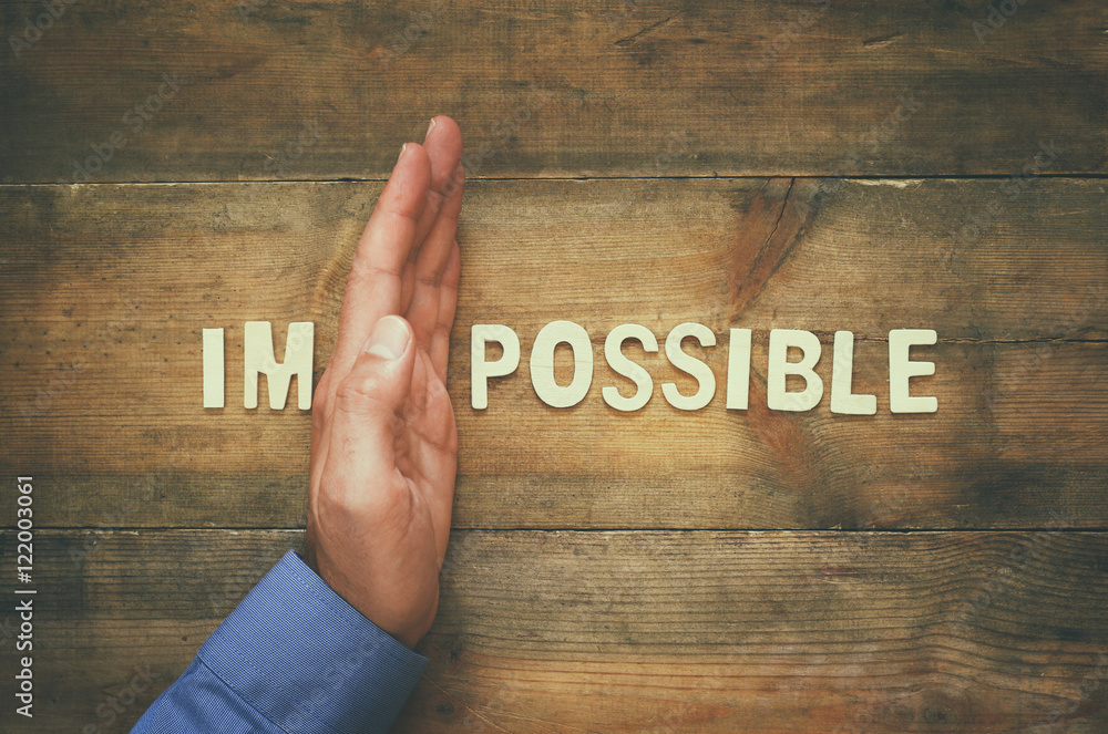 Poster man hand building the wall between of the letters im from the word impossible so it says possible.