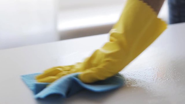 hand spraying cleanser and cleaning table with rag