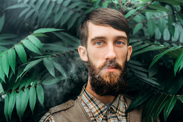 Young man with beard vaping an electronic cigarette outdoor. hipster smoke vaporizer.
